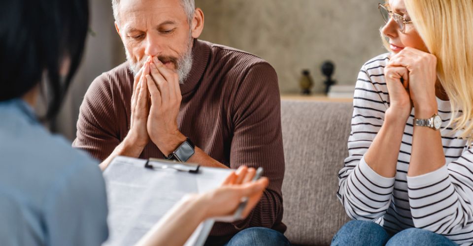 Worried middle aged couple sitting in a sofa with a financial advisor